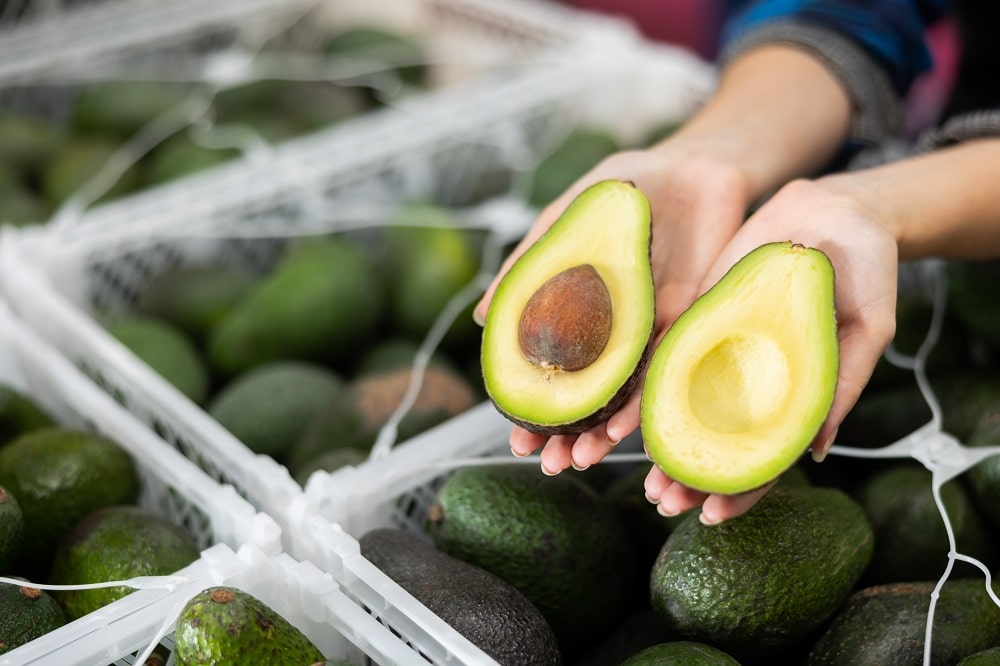 Close up,Of,Two,Halves,Of,Ripe,Hass,Avocado,In,Hands