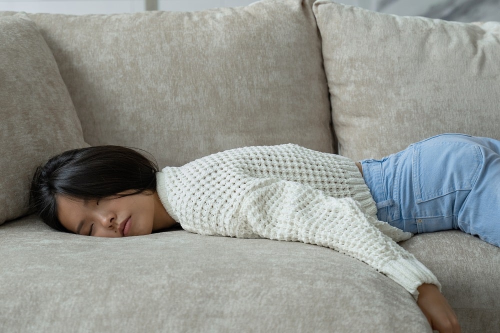 Exhausted,Young,Asian,Woman,Falls,On,The,Sofa.,A,Tired,