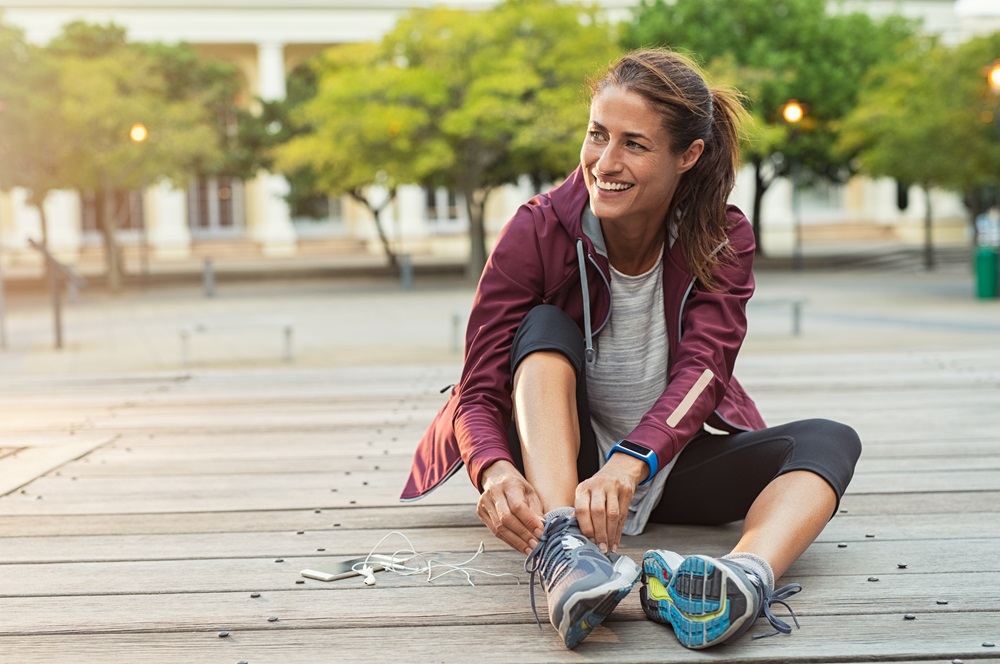 Mature,Fitness,Woman,Tie,Shoelaces,On,Road.,Cheerful,Runner,Sitting